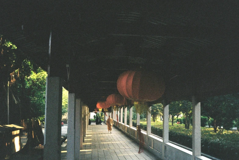 an outdoor covered walkway at a park with people sitting on benches