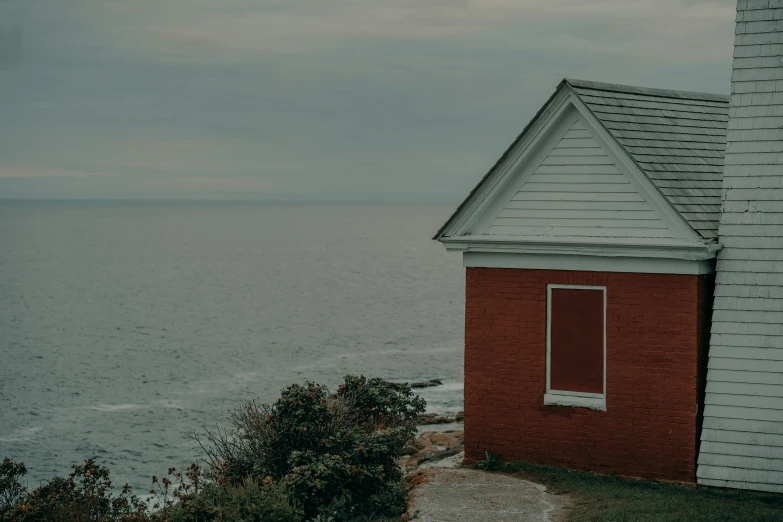 a window on a brick building overlooks the ocean