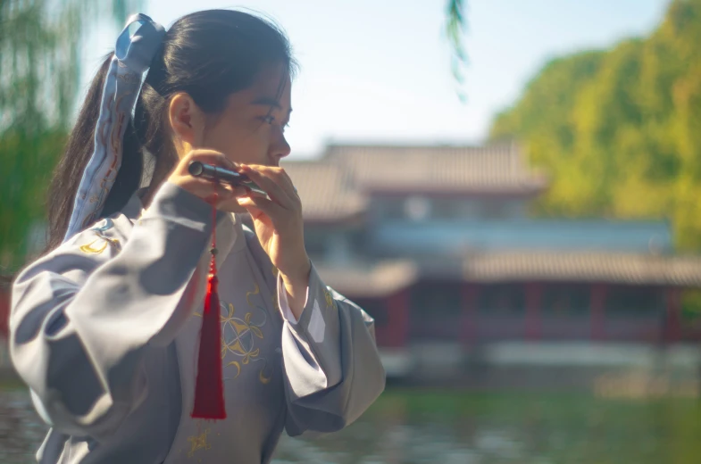 an asian woman in traditional clothing holds her hand up and looks at the water