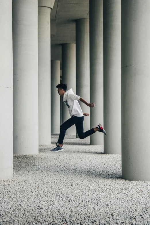 the man is jumping over the ground between the columns