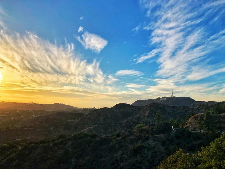 a bright sky over some mountains with trees