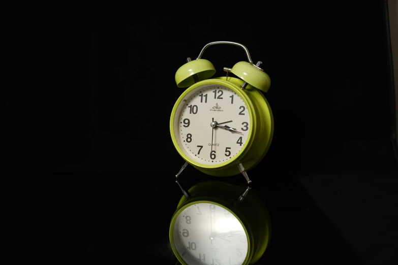 an alarm clock on a black surface with no people around it