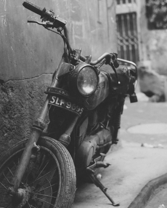 an old motorcycle leaning on the wall of an alley