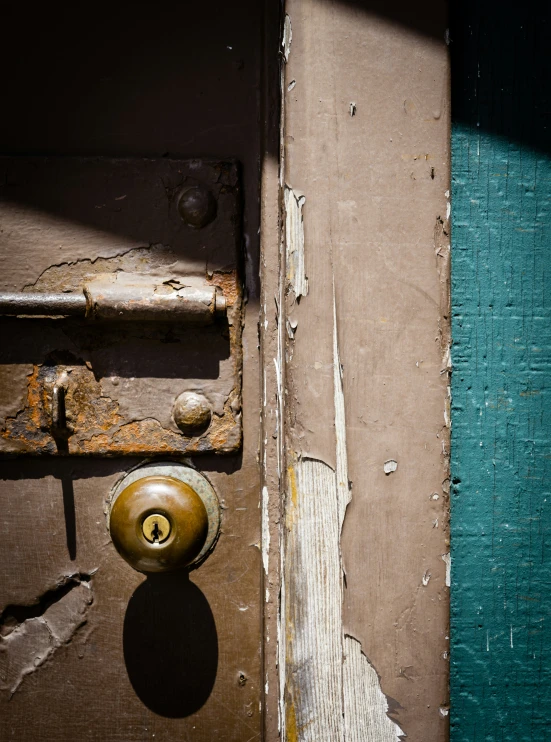 an open door with peeling paint and lock on a wood door