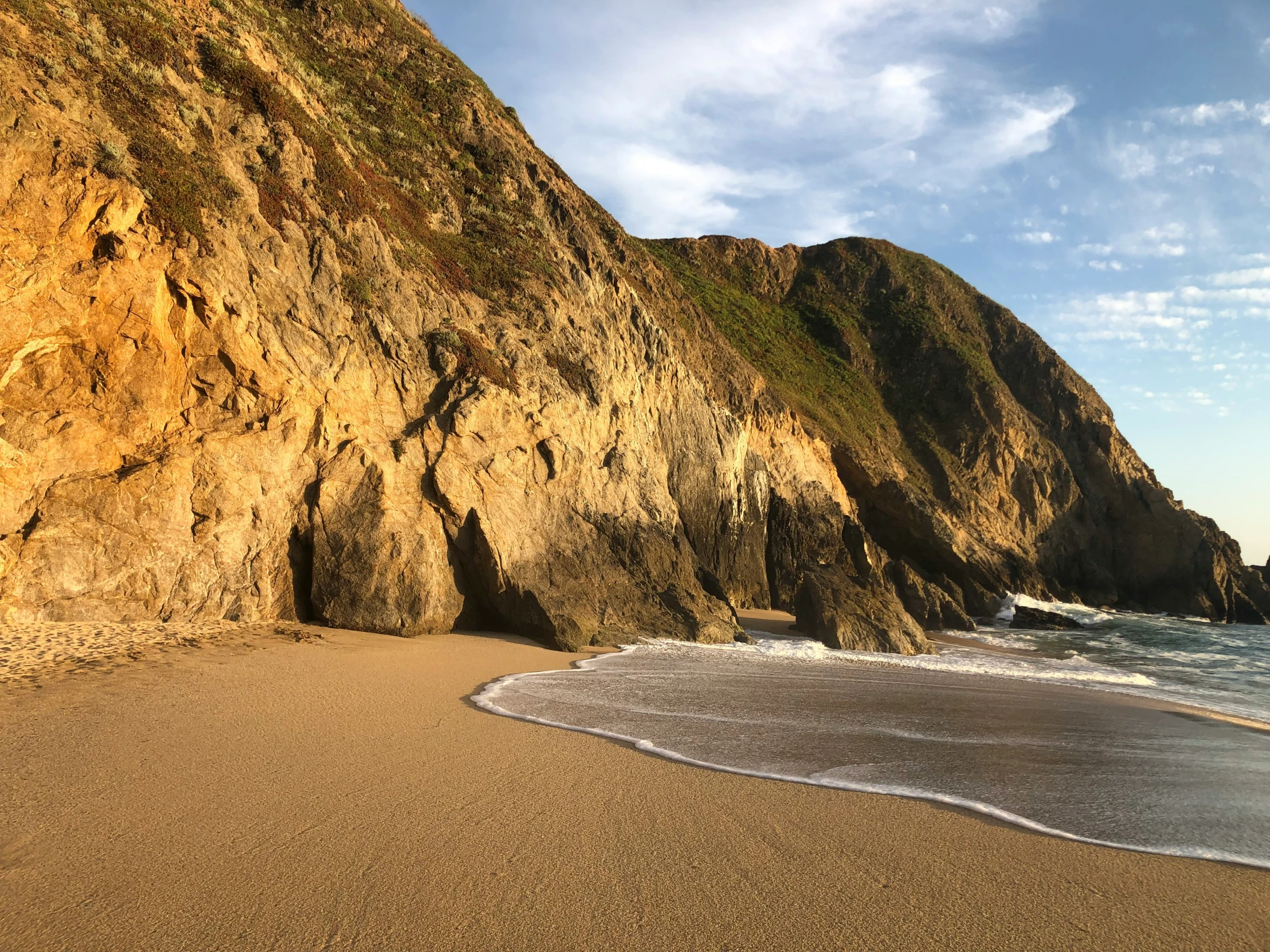 there is a sandy beach next to an artificial cliff