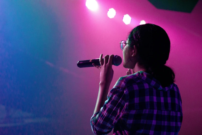 a woman holding a microphone in front of a purple background