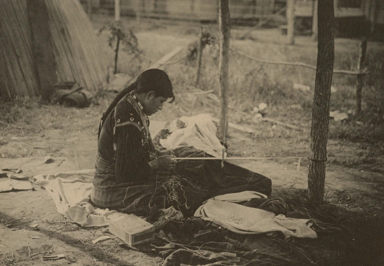 a woman sitting next to a tree next to clothes