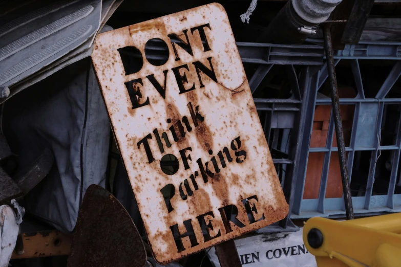 a rusted sign with the word, don't even tell they are