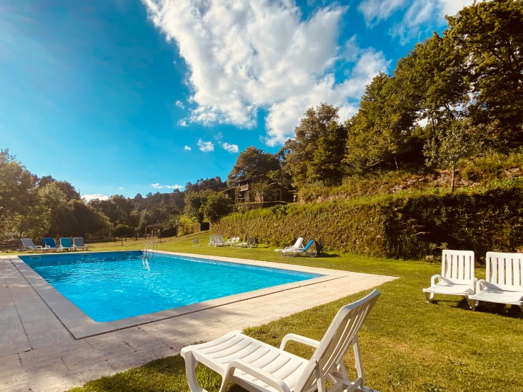 an empty swimming pool and lawn chairs on a sunny day