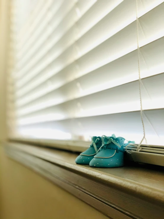 small green shoe sitting on the ledge of a window