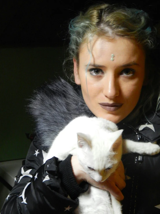 a woman with black hair is holding a white cat