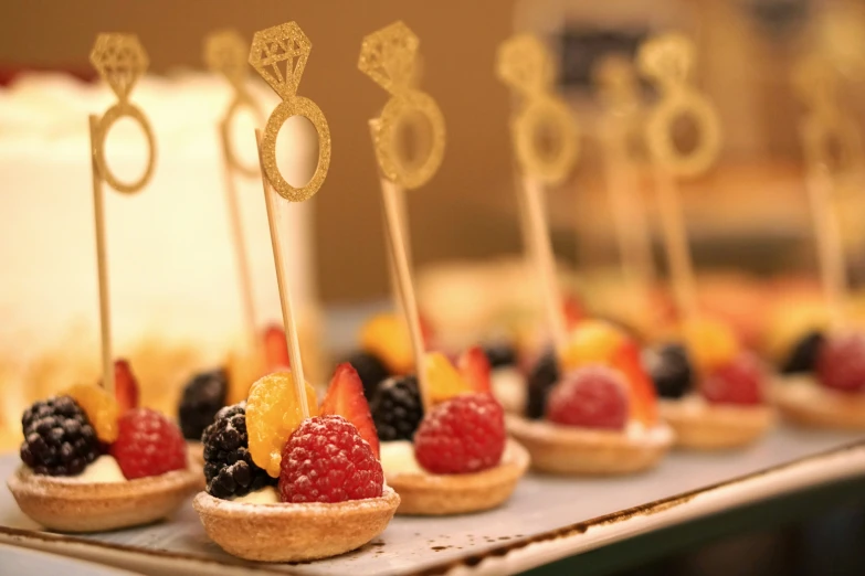 little tarts with fruits on top of them and a cake in the background