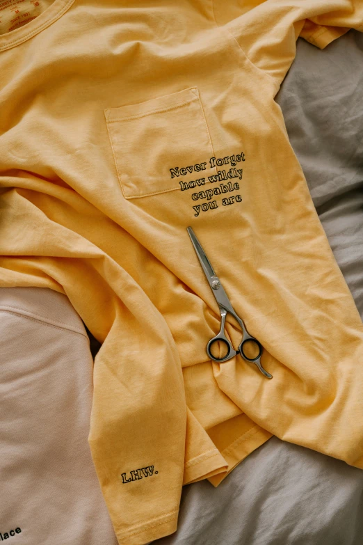 a yellow tshirt and a pair of scissors lying on top of the sheet