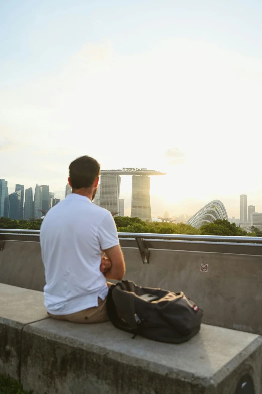 a person sits on a concrete bench, with a bag in front of them