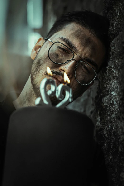 a man in glasses looking at candles from a lighter