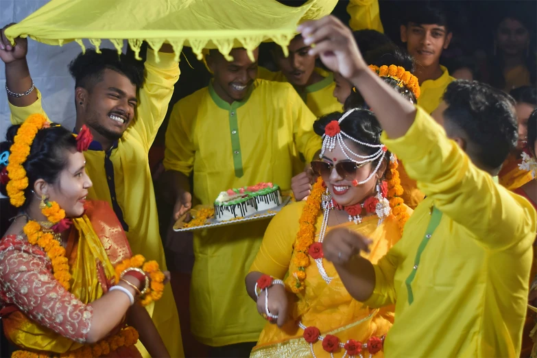 a group of people standing around each other near a cake