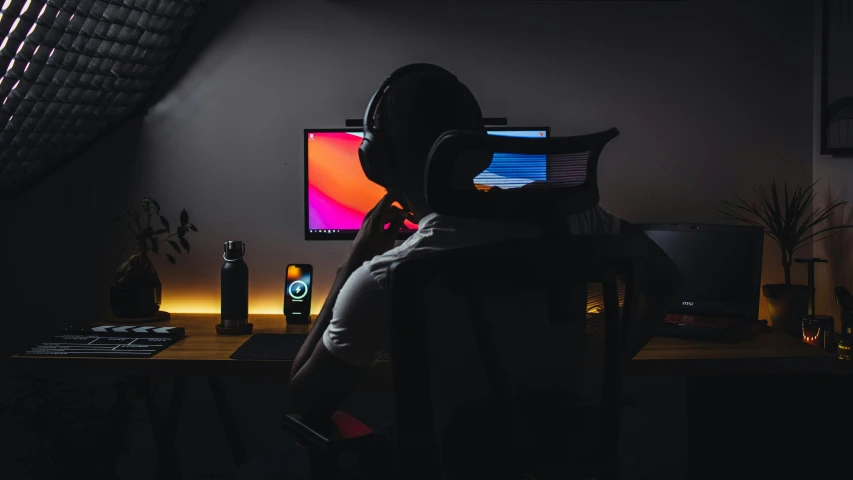 man wearing headphones at a computer in the dark