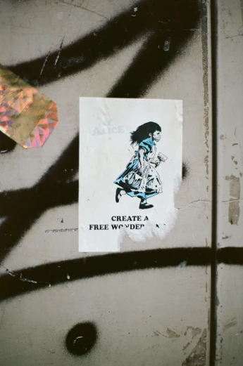 a sticker on a graffitied wall saying create a free from gravity