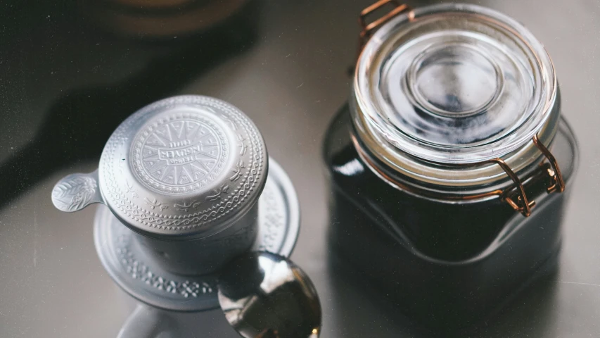 a jar of liquid is sitting next to the spoon