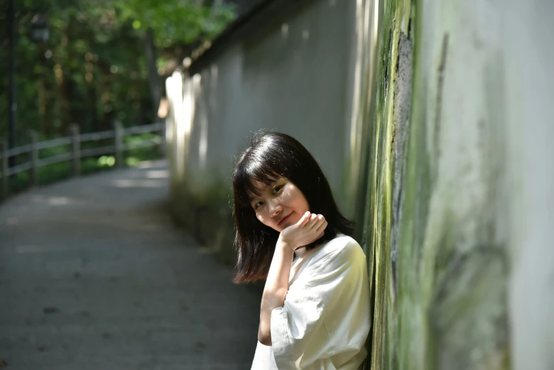 a woman leaning against a wall next to a walkway