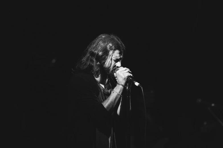 a singer is performing in the dark, with his hands clasped