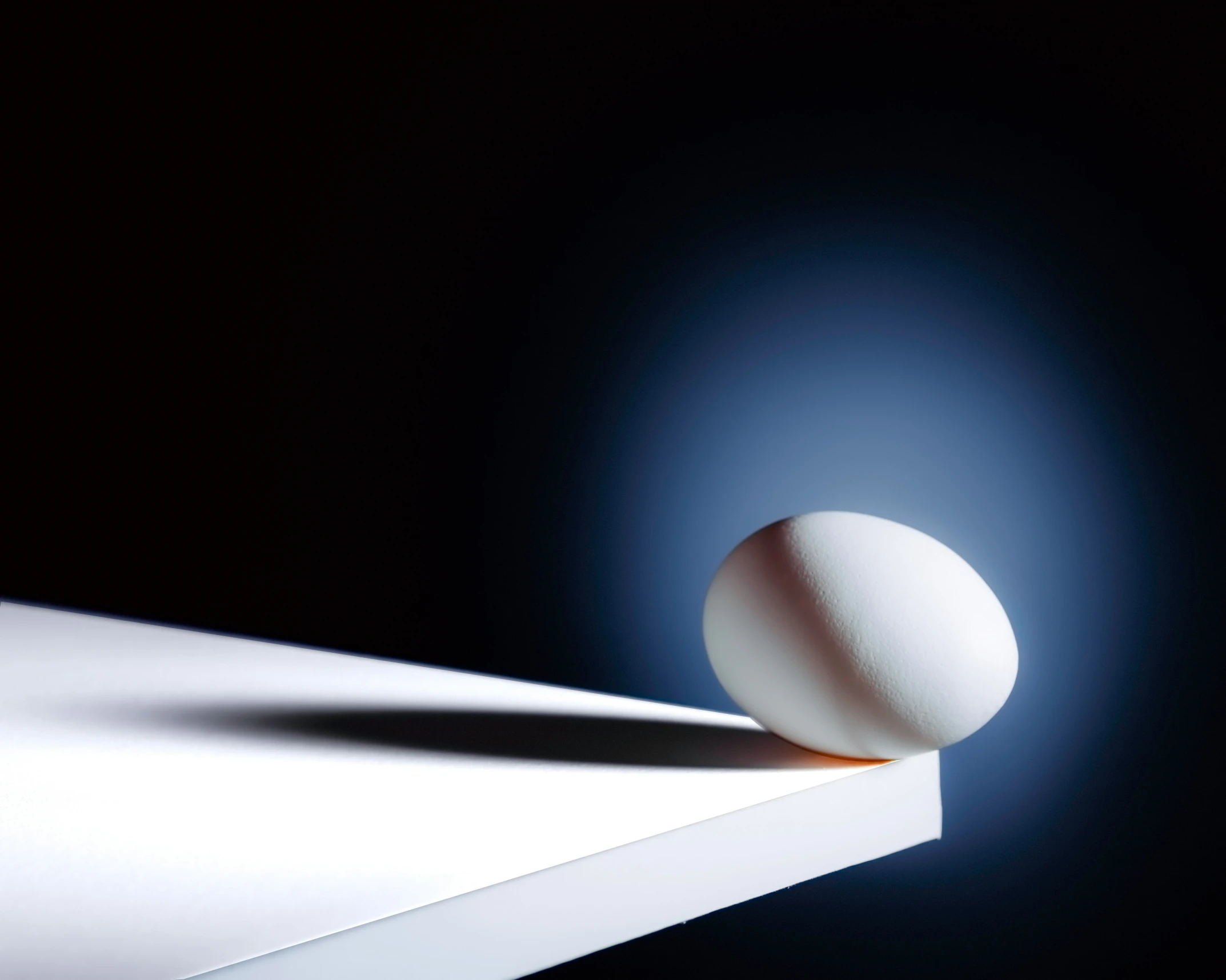 an egg on top of a shelf casting a shadow