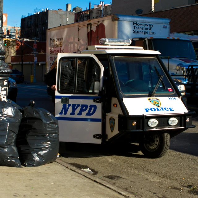 a nypd bus and garbage bags near a city street