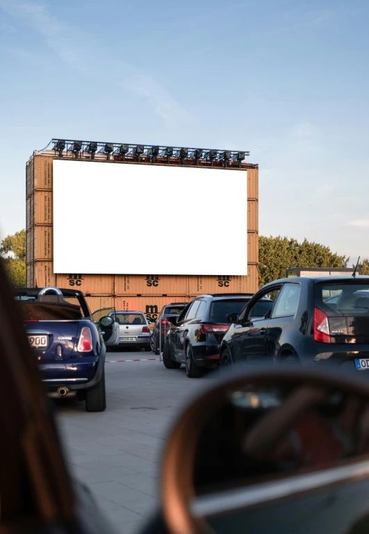 a car parked in front of a big screen in a parking lot