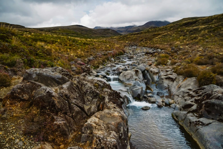 a rocky river runs through a hilly valley