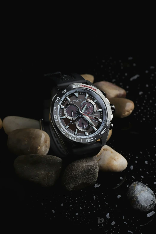 an elegant black watch with a rose - like pattern is sitting on some rocks
