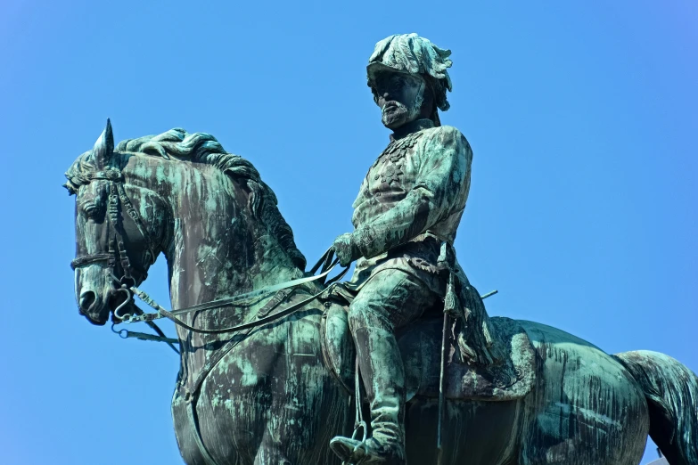 the statue of a man sitting on a horse with his legs crossed