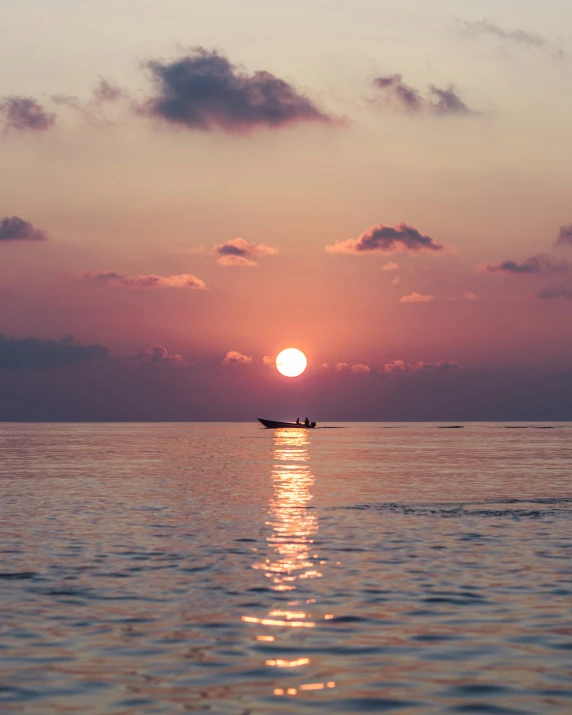 the sun setting over the water with some ships