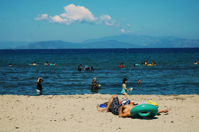 people relaxing and playing on the beach with an inflatable ball