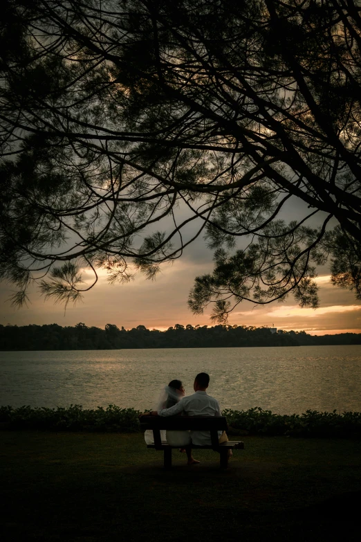 two people sitting on a park bench near the water