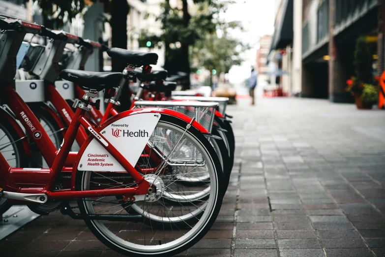 several red bikes lined up on the street in front of an orange building