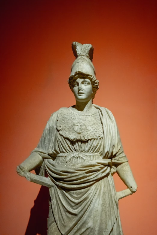 an ancient statue with a red background in the day