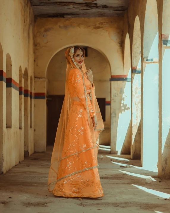 the woman in an orange dress is wearing a tulle and veil