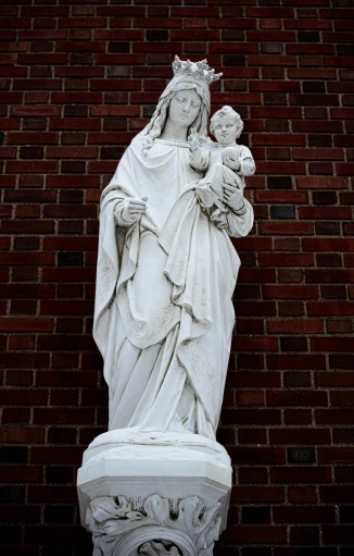 statue of mary and baby jesus against a brick wall