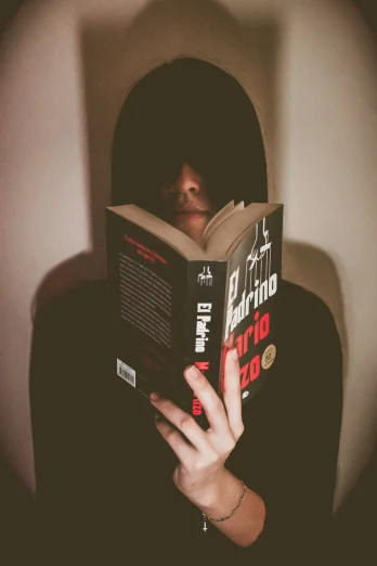 a person with glasses reading a book in the dark