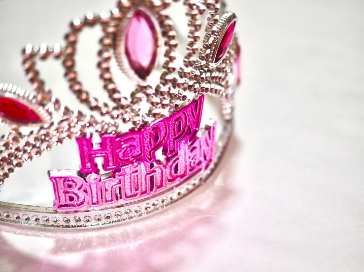a tiara sitting on top of a table covered with pink letters