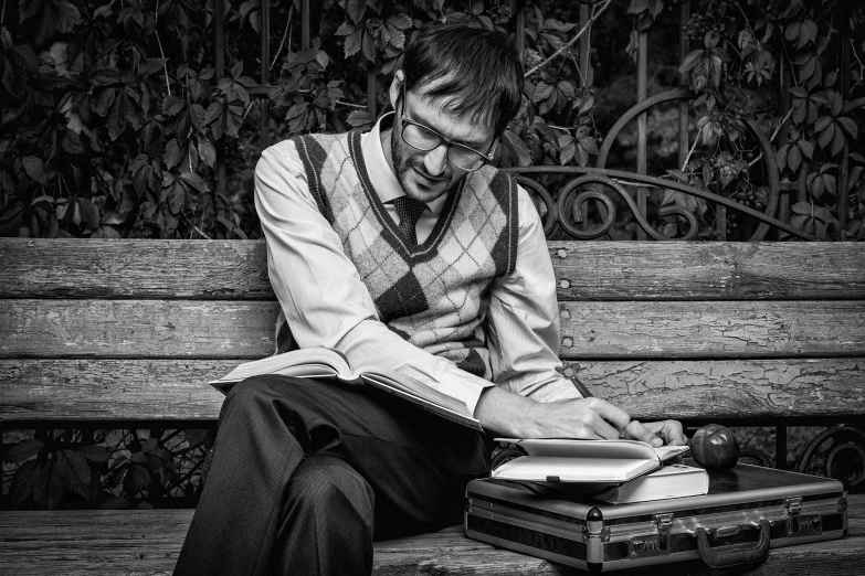 a man sits on a bench while looking through a book