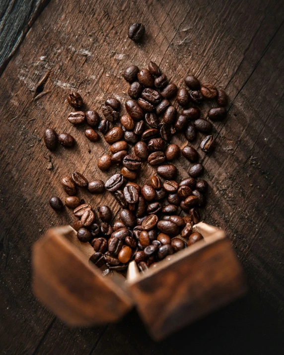 several roasted coffee beans in a wooden scoop on a table