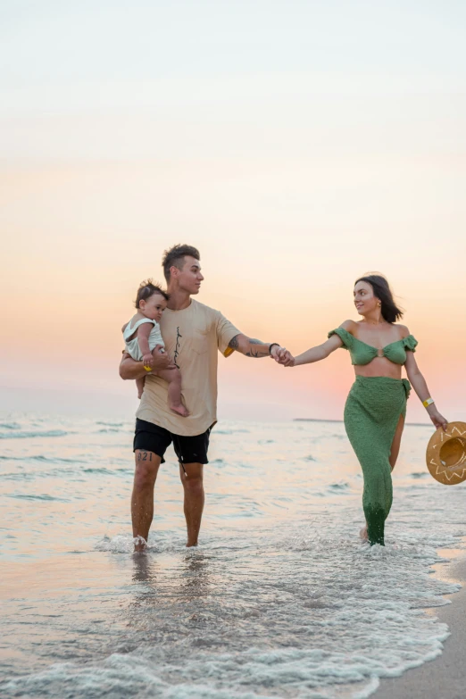 a man and woman holding a baby as they walk into the ocean