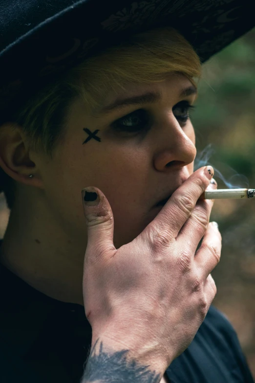 a person smoking a cigarette while wearing a hat