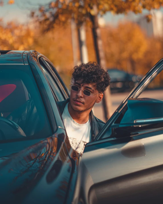 a man in a white shirt leaning out the door of a car