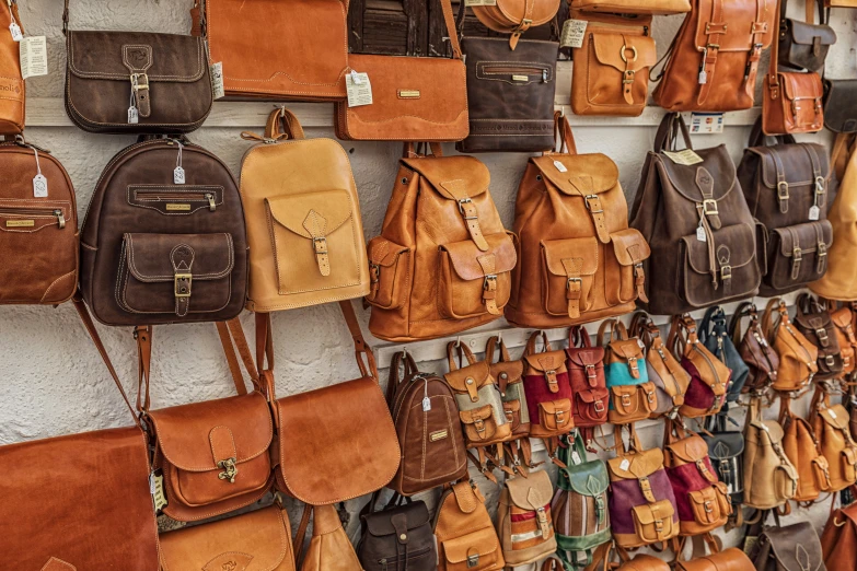 a wall filled with brown leather handbags hanging on a wall