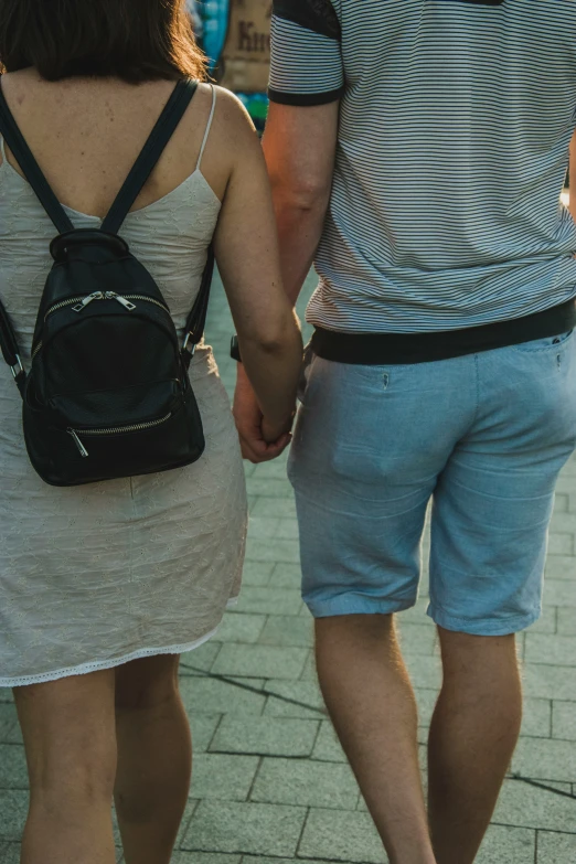 a man and woman holding hands while walking