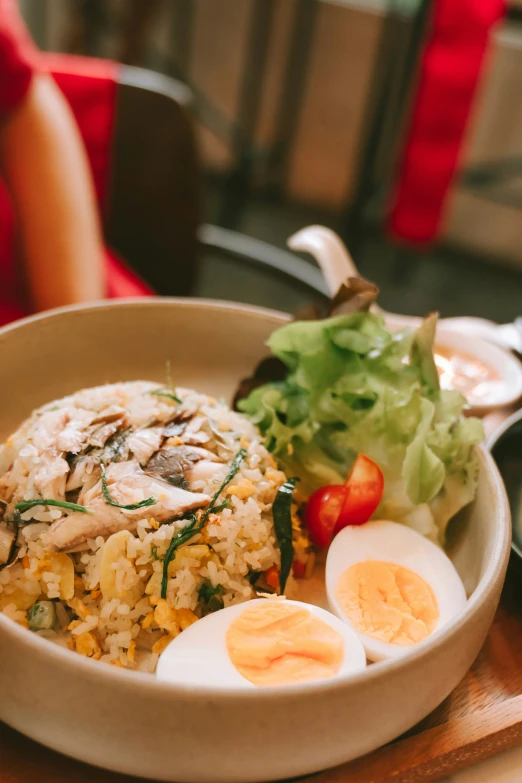 a white bowl with rice, sliced eggs and greens on top