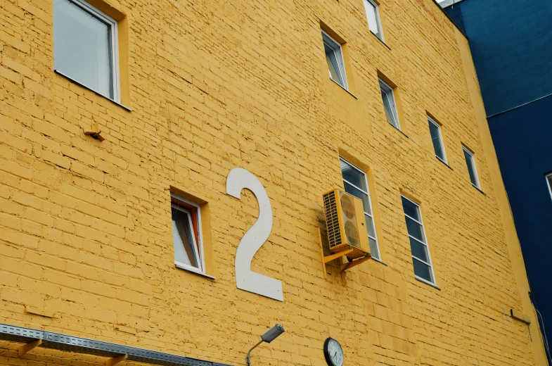 a yellow building that has a clock on the wall