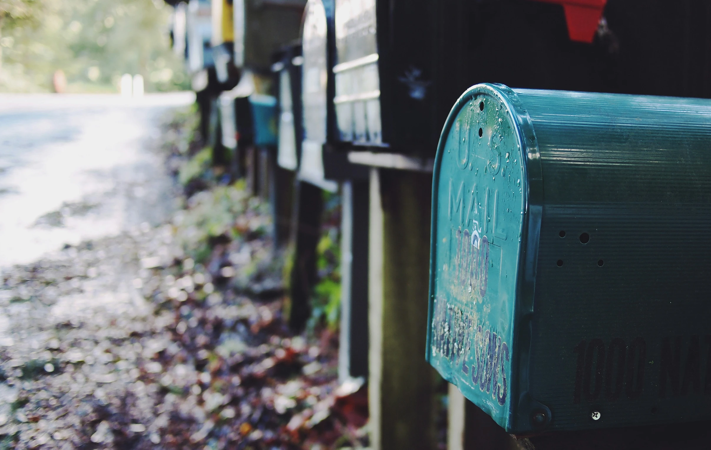 two green mail boxes that are on a pole